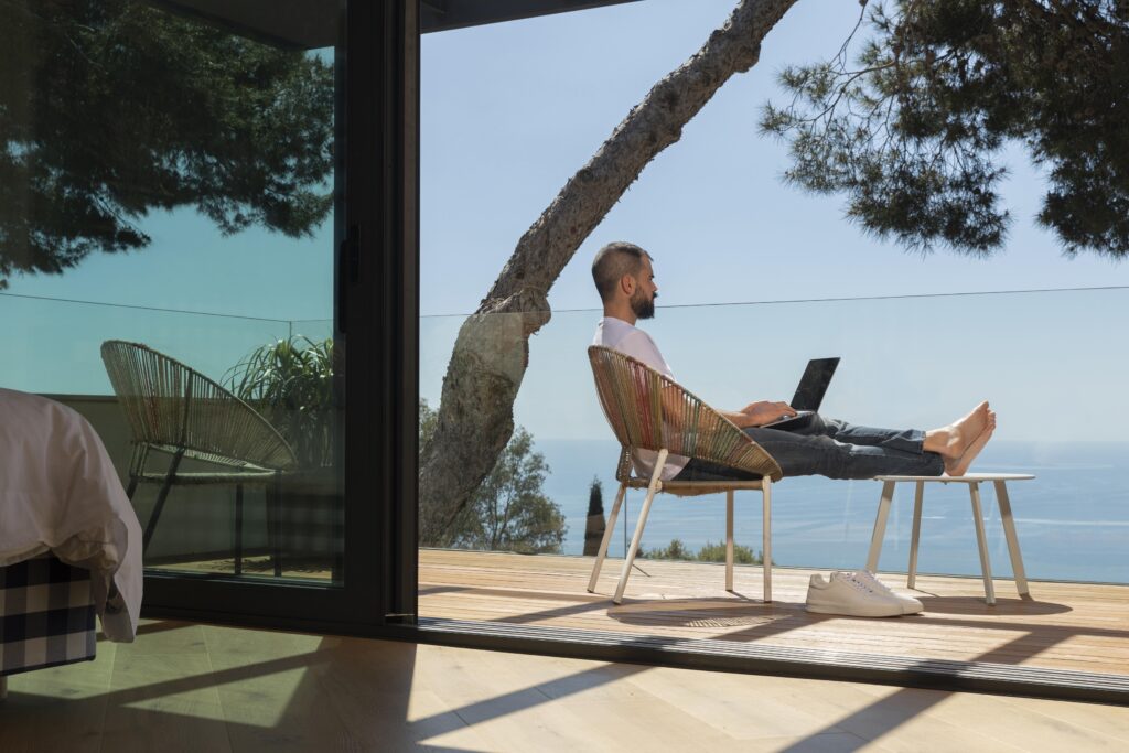 man working on his computer remotely on the balcony 