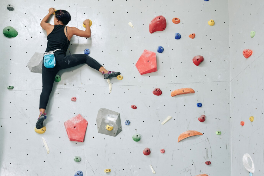 Woman climbing a wall representing one of the barriers faced by women in tech